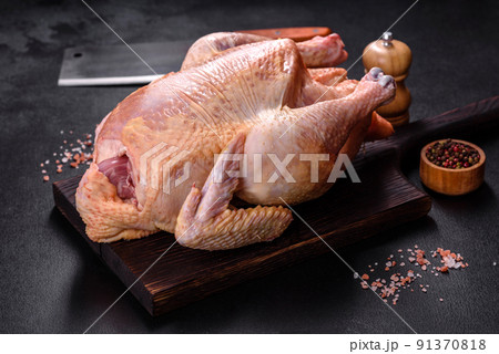 Raw turkey or chicken with salt, spices and herbs on a wooden cutting board. Preparing a festive table Raw turkey or chicken with salt, spices and herbs on a wooden cutting board. Preparing a festive table 91370818