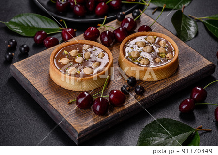 Delicious fresh nougat and nut tart with fresh berries on a wooden cutting board 91370849