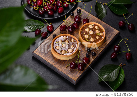 Delicious fresh nougat and nut tart with fresh berries on a wooden cutting board Delicious fresh nougat and nut tart with fresh berries on a wooden cutting board 91370850