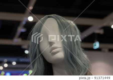 The head of a white female mannequin with gray hair against a dark ceiling with white beams. Close-up photo. Soft focus. The head of a white female mannequin with gray hair against a dark ceiling with white beams. Close-up photo. Soft focus. 91371449