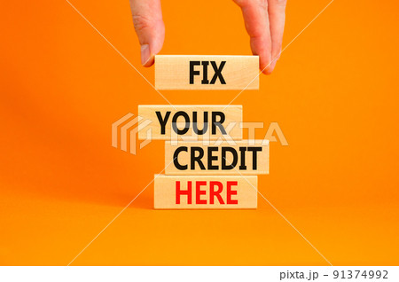 Fix your credit here symbol. Concept words Fix your credit here on wooden blocks on a beautiful orange table orange background. Businessman hand. Business, finacial and fix your credit here concept. 91374992