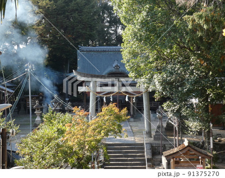枯葉を燃やす煙がたなびく棚倉孫神社の冬の風景 91375270
