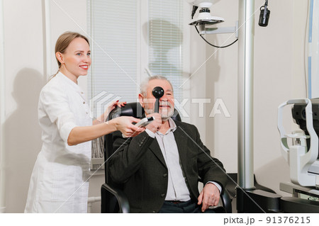 ophthalmologist diagnoses elderly man's vision on a sign projector. ophthalmologist diagnoses elderly man's vision on a sign projector. 91376215