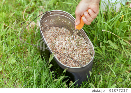 Tourist breakfast. Buckwheat in an iron bowl next to the barbecue. Travel concept. Tourist breakfast. Buckwheat in an iron bowl next to the barbecue. Travel concept. 91377237
