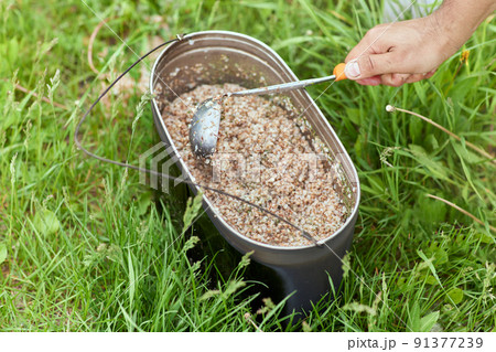 Tourist breakfast. Buckwheat in an iron bowl next to the barbecue. Travel concept. 91377239