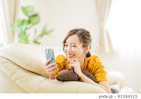 スマホでネットショッピングを楽しむ若い女性 スマホでネットショッピングを楽しむ若い女性 91384525