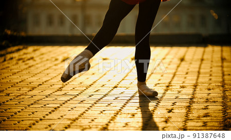 Feet of young woman ballerina dancing on the roof in the pointe shoes - yellow sunset 91387648