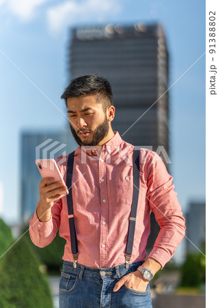 Serious and relaxed businessman using mobile outside a business center. Serious and relaxed businessman using mobile outside a business center. 91388802