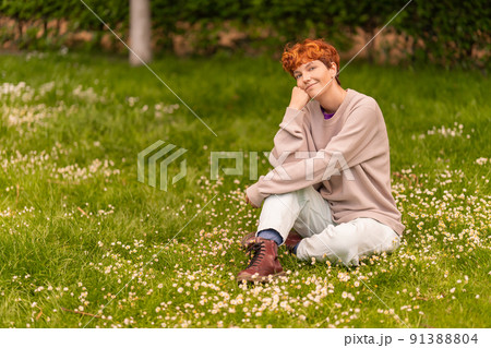 Glad lesbian woman relaxing on blooming lawn in summer Glad lesbian woman relaxing on blooming lawn in summer 91388804