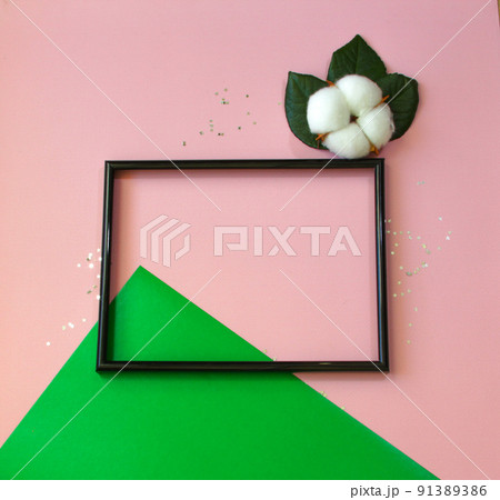 Summer modern composition. Black photo frame, green leaves and flower cotton of tree on pastel pink background. Flat lay, top view, copy space Summer modern composition. Black photo frame, green leaves and flower cotton of tree on pastel pink background. Flat lay, top view, copy space 91389386