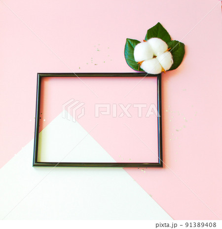 Summer modern composition. Black photo frame, green leaves and flower cotton of tree on pastel pink background. Flat lay, top view, copy space Summer modern composition. Black photo frame, green leaves and flower cotton of tree on pastel pink background. Flat lay, top view, copy space 91389408