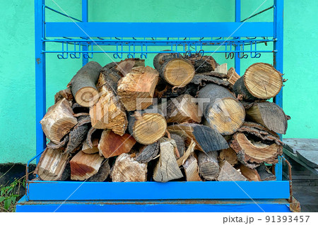 Pile of chopped firewood stacked in woodpile for heating in winter or for fireplace. Near by wall of residential building. Close-up. Pile of chopped firewood stacked in woodpile for heating in winter or for fireplace. Near by wall of residential building. Close-up. 91393457