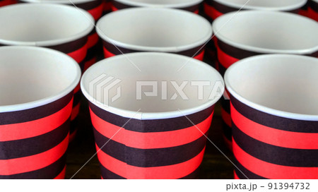 Row of red and black disposable eco friendly paper cup for coffee or hot beverage on dark backdrop. Selective focus. 91394732
