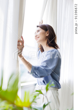 カーテンを開ける女性 91396872