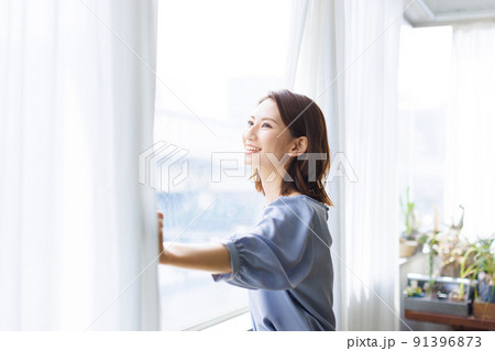 カーテンを開ける女性 91396873