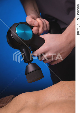 Sports percussion massage in the medical office of the gym. The masseur makes massage exercises. Percussion therapy for regenerating sports body massage. Sports injury rehabilitation concepts. 91396900