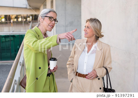 Businesswoman pointing far away while talking with colleague 91397291