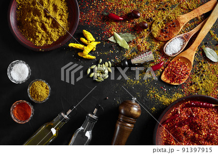 Set of indian spices on black background - green cardamom, turmeric powder, coriander seeds, cumin, and chili, top view Set of indian spices on black background - green cardamom, turmeric powder, coriander seeds, cumin, and chili, top view 91397915