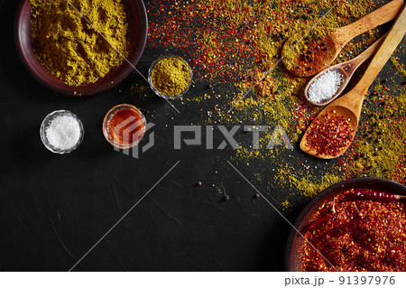 Set of indian spices on black background - green cardamom, turmeric powder, coriander seeds, cumin, and chili, top view 91397976