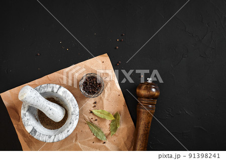 White mortar and pestle with dried peppers in flat lay on black background 91398241