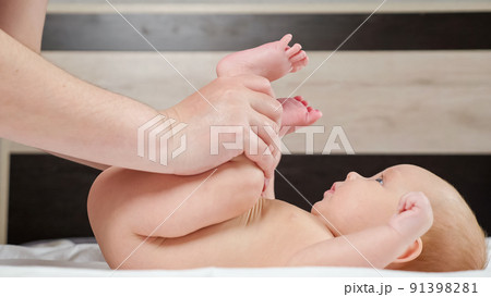 Grandmother does leg exercise with newborn baby girl on bed 91398281