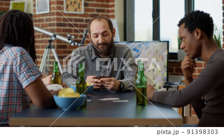 Competitive people playing board games with cards at table, enjoying tactics with leisure activity. Positive group of friends having fun together with strategy card competition. Close up. 91398303