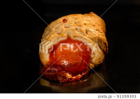 Baked bun with red strawberry jam in electric oven: close up, black background Baked bun with red strawberry jam in electric oven: close up, black background 91399303