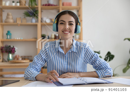 Smiling businesslady in headphones sit at desk look at camera Smiling businesslady in headphones sit at desk look at camera 91401103