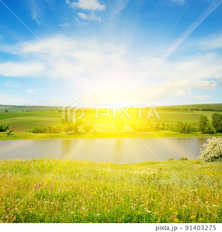 Meadow, lake, agricultural fields and sunrise on blue sky. Meadow, lake, agricultural fields and sunrise on blue sky. 91403275