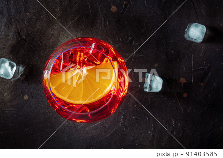 Aperol cocktail with an orange slice and ice cubes close-up, Italian drink 91403585