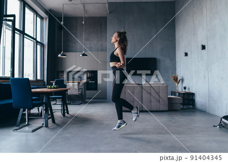 Fit woman with jump rope at home doing skipping workout. Fit woman with jump rope at home doing skipping workout. 91404345