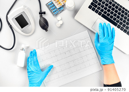 Top view of doctor's hand with result of the survey, digital blood pressure monitor on white table 91405270