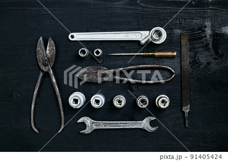 Copy space of working tools on a black wooden surface. Nippers, wrench keys, pliers, screwdriver. Top view. 91405424