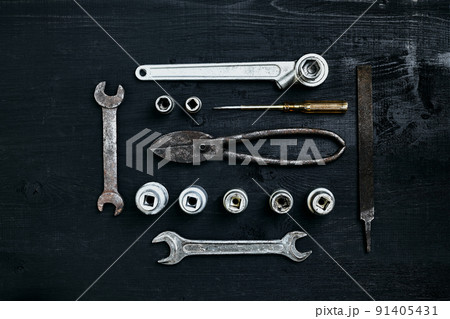 Copy space of working tools on a black wooden surface. Nippers, wrench keys, pliers, screwdriver. Top view. 91405431