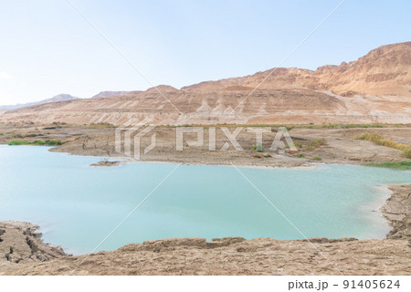 Sinkhole filled with turquoise water, near Dead Sea coastline. Hole formed when underground salt is dissolved by freshwater intrusion, due to continuing sea-level drop.  91405624