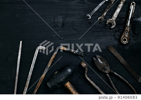 Old, rusty tools lying on a black wooden table. Hammer, chisel, metal scissors, wrench. Old, rusty tools lying on a black wooden table. Hammer, chisel, metal scissors, wrench. 91406083
