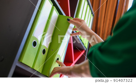Secretary takes out business folder with documents from cabinet Secretary takes out business folder with documents from cabinet 91407322
