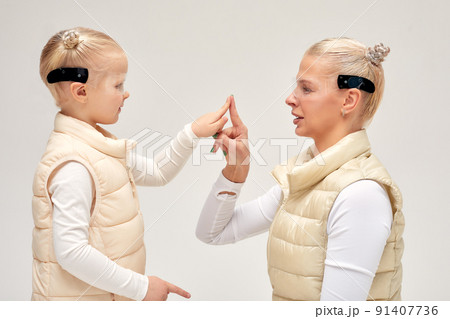 Woman with little girl in futuristic costume wearing smart led glasses of virtual reality while touching air. Augmented reality game, future technology, AI concept. VR. Woman with little girl in futuristic costume wearing smart led glasses of virtual reality while touching air. Augmented reality game, future technology, AI concept. VR. 91407736