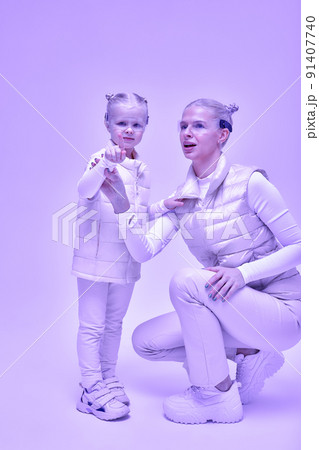 Woman with little girl in futuristic costume wearing smart led glasses of virtual reality while touching air. Augmented reality game, future technology, AI concept. VR. Neon light. Woman with little girl in futuristic costume wearing smart led glasses of virtual reality while touching air. Augmented reality game, future technology, AI concept. VR. Neon light. 91407740