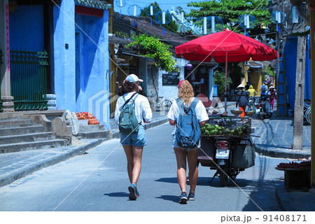 世界遺産の古都、ホイアンの昼下がり、欧米人観光客と、果物売りのバイク 91408171