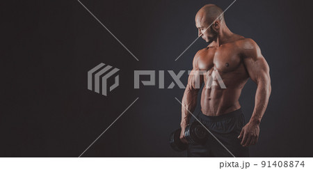 Muscular and fit young bodybuilder fitness male model posing over black background. copy space Muscular and fit young bodybuilder fitness male model posing over black background. copy space 91408874