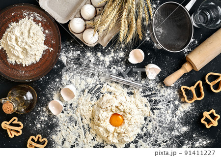 Woman smashes an egg using knife while kneading a pastry. Studio shot. Top view Woman smashes an egg using knife while kneading a pastry. Studio shot. Top view 91411227