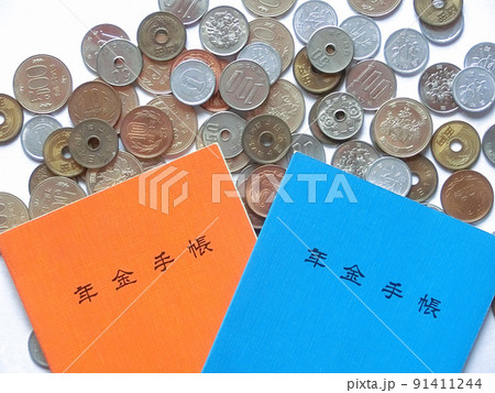 散らばった日本の硬貨と重なった橙色と青色の年金手帳 散らばった日本の硬貨と重なった橙色と青色の年金手帳 91411244