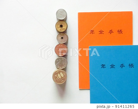 重なった橙色と青色の年金手帳と縦に並んだ日本の硬貨と白背景のコピースペース 重なった橙色と青色の年金手帳と縦に並んだ日本の硬貨と白背景のコピースペース 91411265