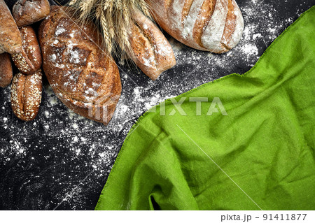Different bread with flour and spikelets of wheaton black background Different bread with flour and spikelets of wheaton black background 91411877
