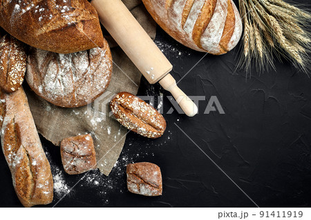Bakery - gold rustic crusty loaves of bread and buns on black chalkboard background. Bakery - gold rustic crusty loaves of bread and buns on black chalkboard background. 91411919