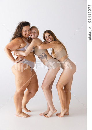 Group portrait of beautiful women posing in underwear isolated over grey studio background. Different body shape and size 91412077