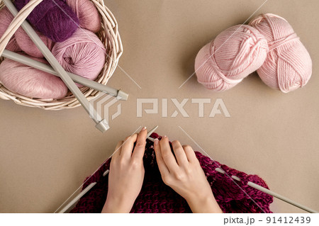 Close-up of female hands knitting wool sweater or plaid lilac color. Top view 91412439