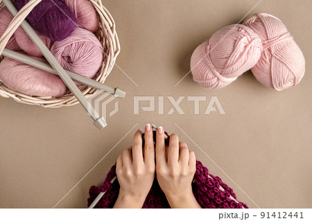 Close-up of female hands knitting wool sweater or plaid lilac color. Top view 91412441
