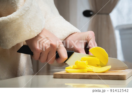 Close-up of female hands cutting fresh peeled potatoes tomatoes on cutting board at home kitchen Close-up of female hands cutting fresh peeled potatoes tomatoes on cutting board at home kitchen 91412542